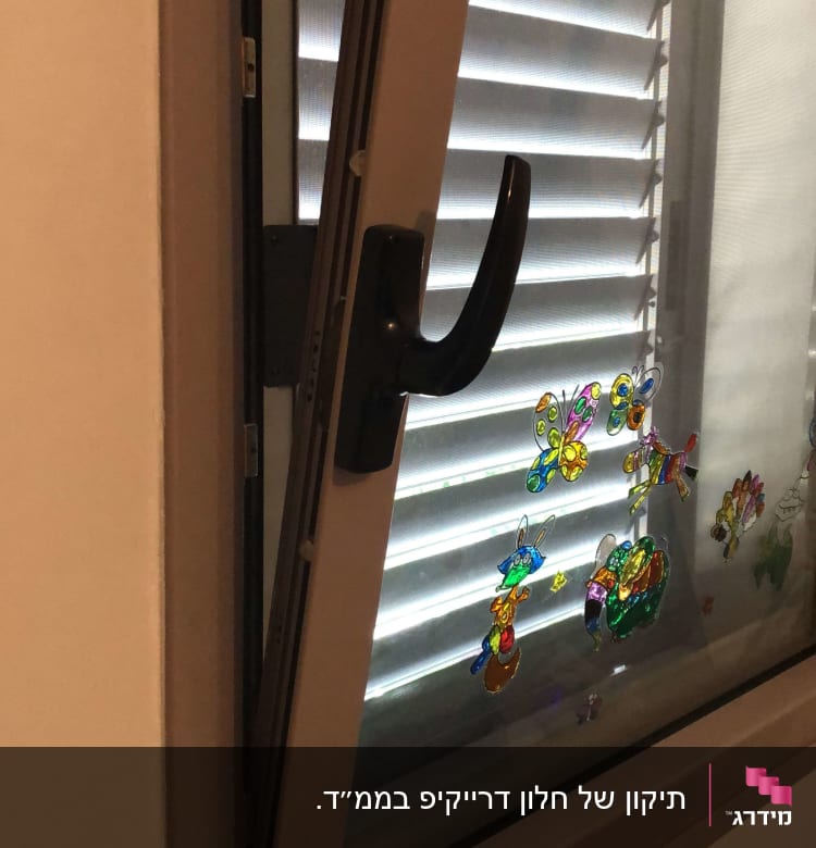 תריסים לבנים מאחורי חלון פתוח עם מדבקות צבעוניות